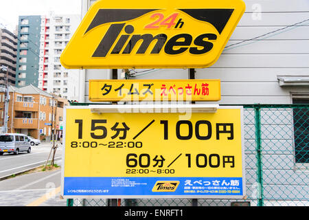 Japanese car parking sign for paid spaces. Open 24 hours, listing prices per 15 minutes between 8:00-22:00 and 60 minutes 22:00-8:00. Stock Photo