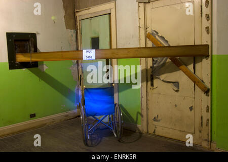 Wheelchair in corner with sign reading not safe in front of elevator door. Stock Photo