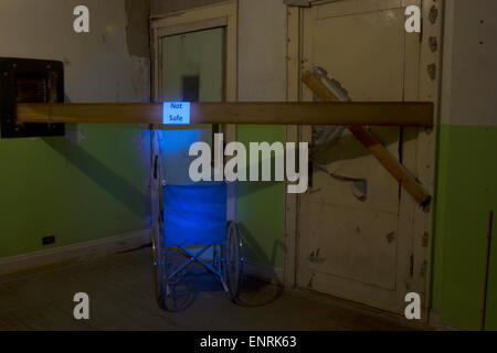 Blue wheelchair with not safe sign in corner of abandoned building. Stock Photo