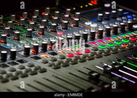 Audio mixer mixing board fader and knobs with selective focus on central buttons, Music mixing console with backlit buttons Stock Photo