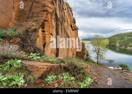 rocky shore and canoe - old sandstone quarry and white canoe or kayak on the shore of Horsetooth Reservoir near Fort Collins, Co Stock Photo