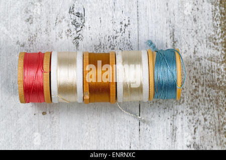 Top view of colorful spools of thread on rustic white wood. Layout in horizontal format. Stock Photo