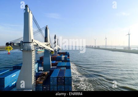 A cargo ship passing by windmills in the port of Rotterdam, Netherlands Stock Photo