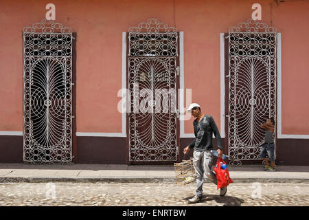 Man with birdcage walking past house with ornate wrought iron grillwork, Trinidad, Cuba Stock Photo