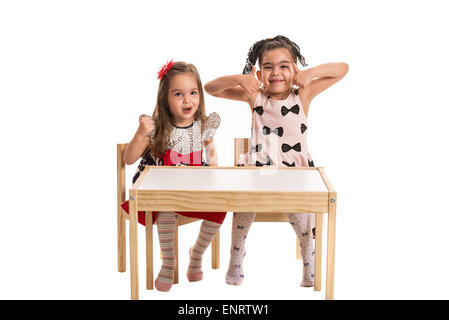Two girls making funny faces and gesturing together isolated on white background Stock Photo