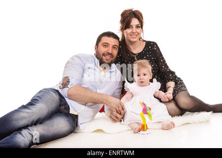 Cheerful family with baby girl sitting on fluffy blanket Stock Photo