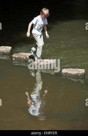 Boy jumping across stepping stones. Stock Photo
