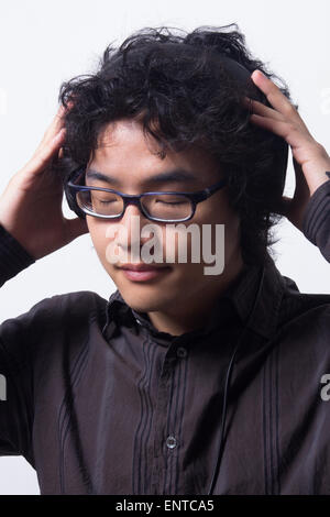 Asian young man wearing head phones with eyes closed Stock Photo