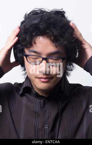 Asian young man wearing head phones with eyes closed Stock Photo