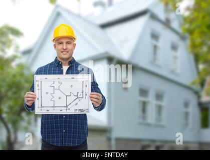 smiling builder with blueprint over house Stock Photo