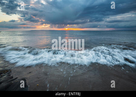 Waves at sunset at Prestwick beach, Ayrshire, Scotland, UK with Isle of Arran on the horizon Stock Photo