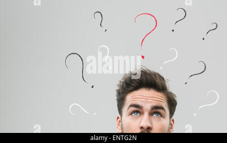 thinking man with many question marks above his head, against grey background Stock Photo