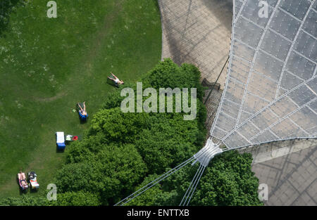 Munich, Germany. 11th May, 2015. People sunbathe in front of the indoor swimming pool at the Olympiapark (Olympic Park) in Munich, Germany, 11 May 2015. PHOTO: PETER KNEFFEL/dpa/Alamy Live News Stock Photo