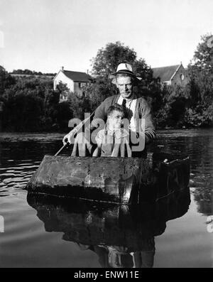 William David Owen is 72 years of age. For thirty years he's been coracle fishing. Now, as he paddles four-year-old Alan Davies across the Teify, he becomes deep in thought. His is a dying industry and young Alan must look elsewhere for work. Circa 1939 Stock Photo