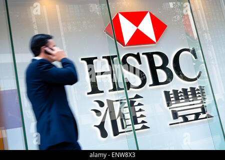 Hong Kong, Hong Kong SAR -November 17, 2014: Motion blured business man passing by an HSBC Bank sign in Hong Kong. HSBC Holdings Stock Photo
