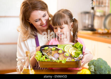 mother and child jolly look at prepared dish of fish Stock Photo