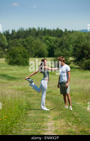 Young man and woman exercising in spring meadow Stock Photo