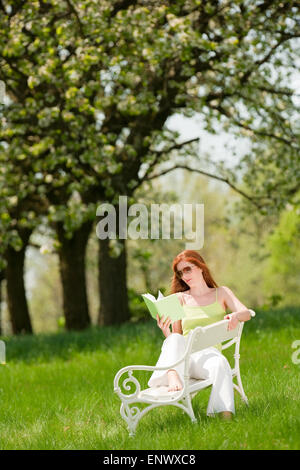 Young woman relaxing under blossom tree in spring Stock Photo
