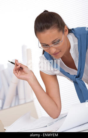 Female architect watching plans and writing notes Stock Photo
