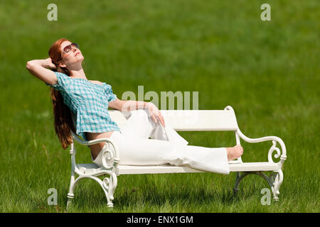 Red hair woman relaxing on white bench in spring Stock Photo