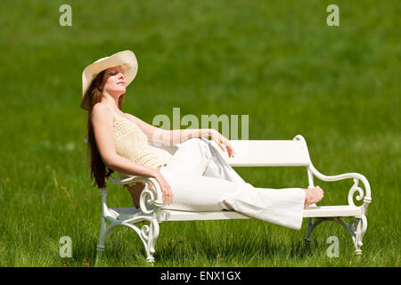 Red hair woman sitting on white bench in spring Stock Photo
