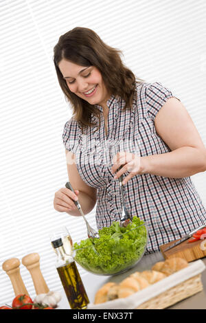 Cook - Plus size happy woman preparing salad in kitchen Stock Photo