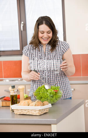 Cook - Plus size happy woman preparing vegetable salad Stock Photo