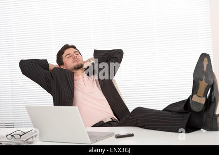 Successful businessman in black suit relaxing at office Stock Photo