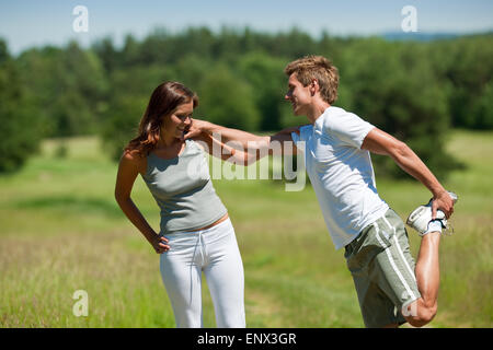 Young man and woman exercising in spring meadow Stock Photo
