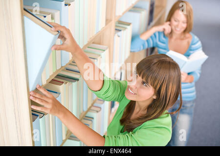 Student in library - two happy woman choose book Stock Photo