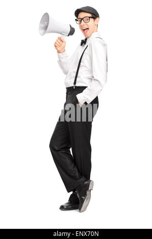 Full length portrait of a young artistic man speaking on a megaphone and leaning against a wall isolated on white background Stock Photo