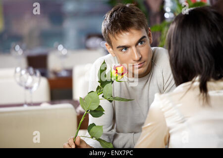 Pair in cafe - man gives to woman a flower Stock Photo