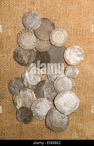 A lot of old silver coins with portraits of kings on the old cloth Stock Photo