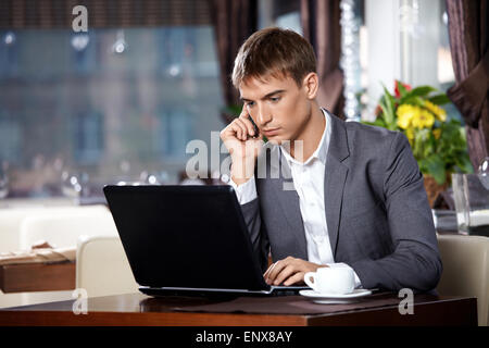 Business man talks to the laptop on mobile in cafe Stock Photo