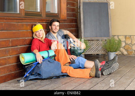 Tramping young couple backpack relax by cottage Stock Photo