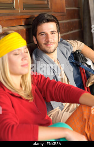 Tramping young couple backpack relax by cottage Stock Photo