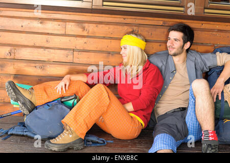 Tramping young couple backpack relax by cottage Stock Photo