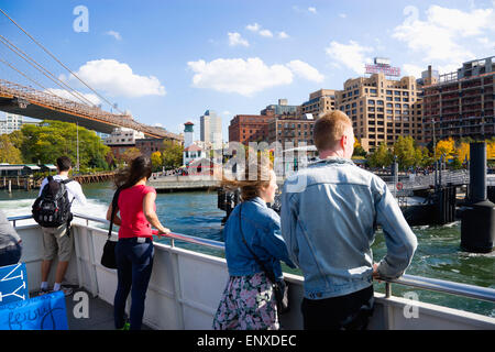 USA, New York State, New York City, Brooklyn Bridge Park, passengers on the deck of the boat to the Wall Street Ferry Pier leaving the Fulton Ferry Landing below the suspension bridge. Stock Photo
