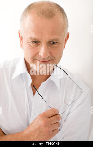Mature businessman thoughtful hold glasses posing Stock Photo
