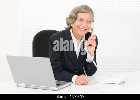 Senior businesswoman smile sit behind office desk Stock Photo