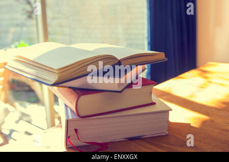 Stack of books on table in sunlight Stock Photo