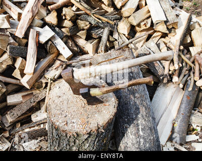 pile of wood, deck for chopping firewood, two axes on village yard Stock Photo