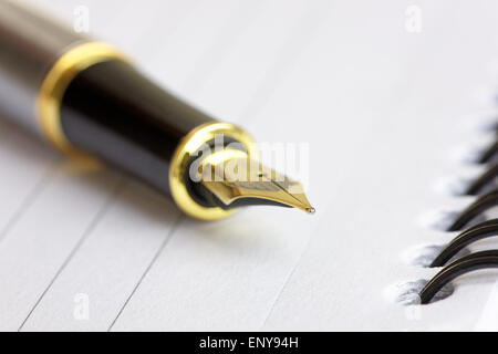 Close up of a gold fountain pen nib on a spiral bound note pad, with shallow d o f Stock Photo