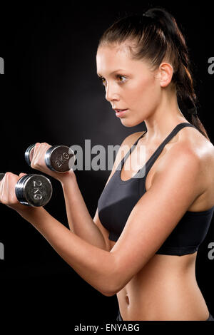 Pretty young woman lifting dumbbells in sportswear Stock Photo