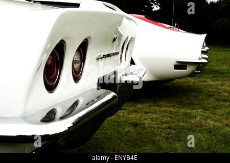 Close-up view of the rear part of a white classic sports car with similar cars seen beyond. Stock Photo