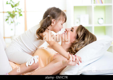 Mom and child daughter embracing and kissing in bed Stock Photo