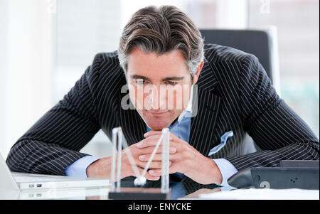 Confident mature businessman looking at kinetic balls Stock Photo