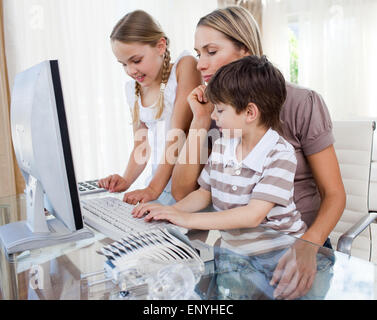 Attractive mother teaching her children how to use a computer Stock Photo