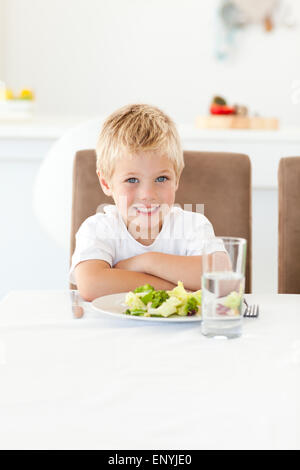Cute little boy ready to eat his salad for lunch sitting at a table Stock Photo