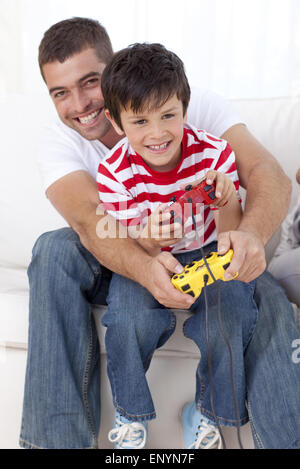 Smiling father and kid playing video games at home Stock Photo